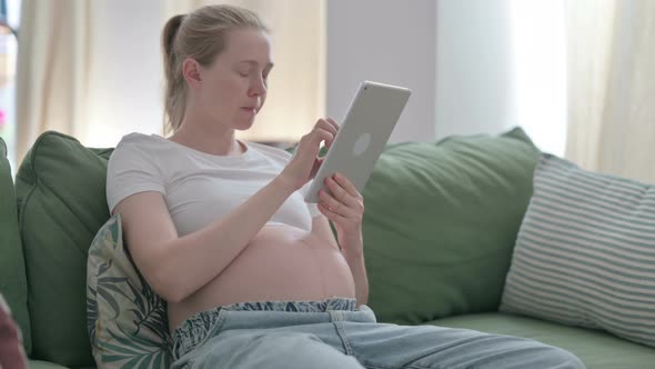Pregnant Woman Using Tablet While Sitting at Home