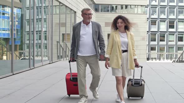 Married Couple with Suitcases Walking Through the Airport or Train Station