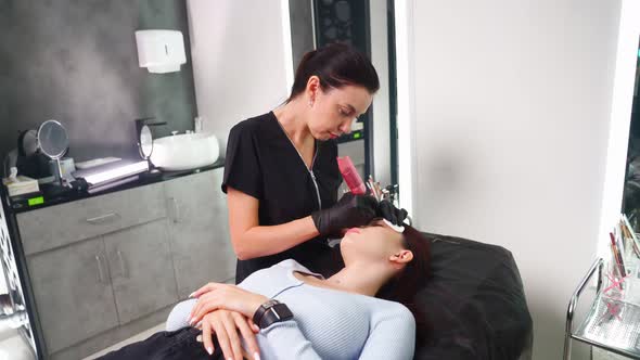 Master Makes Permanent Eyebrow Makeup Procedure to Woman in Beauty Salon