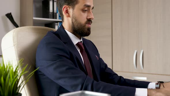 Serious Businessman in His Office Tying His Tie