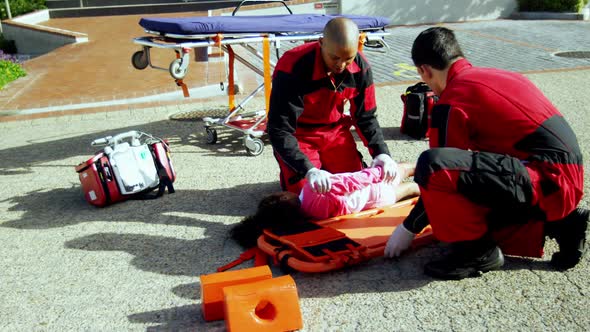 Paramedics putting injured girl onto a backboard
