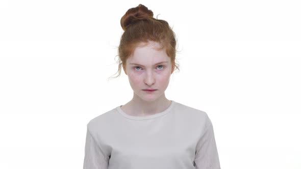 Portrait of Young Redhaired Lady with Topknot Looking Strictly on Camera Being Fed Up of Something