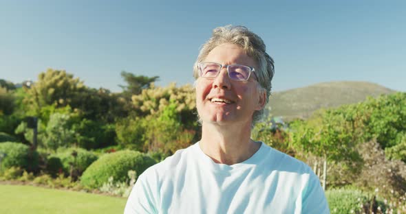 Happy senior caucasian man in garden on sunny day at retirement home