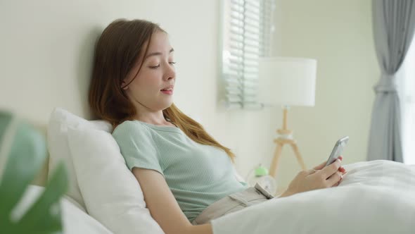 Caucasian beautiful woman chatting on mobile phone in bedroom at home.