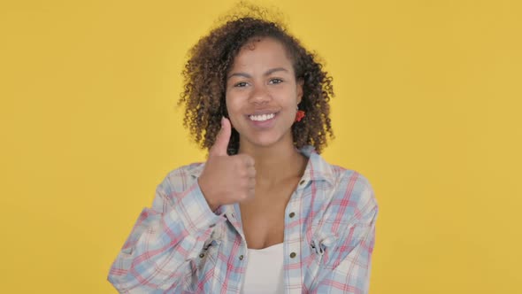 Young African Woman Showing Thumbs Up Sign on Yellow Background