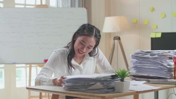 Smiling Asian Woman Enjoys Working With Documents At The Office