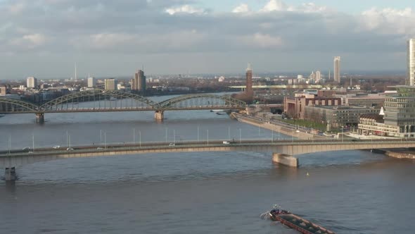 AERIAL: View Over Rhine River in Cologne Cargo Boat Going Under a Bridge in Beautiful Sunlight 