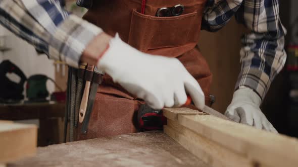 Carpenter Filing a Plank of Wood in His Workshop