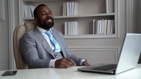 African-American Bearded Man in a Gray Suit and Shirt. The Businessman Is in a Bright Office at the