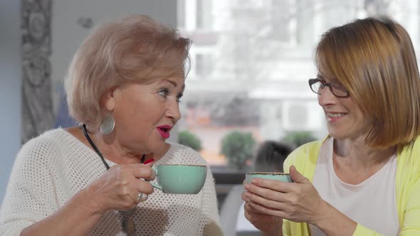 Senior Mother Chatting To Her Daughter Over Cup of Coffee at the Cafe