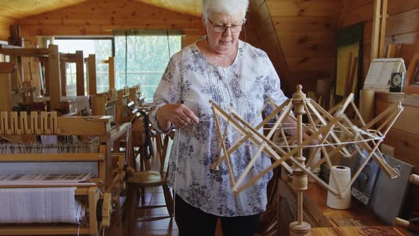 Senior woman operating weaving machine 