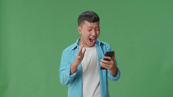 Young Asian Boy Surprise And Say Wow During Use Mobile Phone While Standing On Green Screen