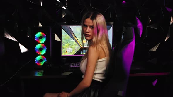 Blonde and Pretty Gamer Girl Turns Away From the PC Monitor and Looking in the Camera in Neon