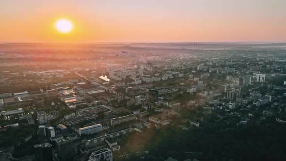 Aerial drone view of Chisinau at sunrise. Multiple buildings, trees, parks, roads with cars. Moldova