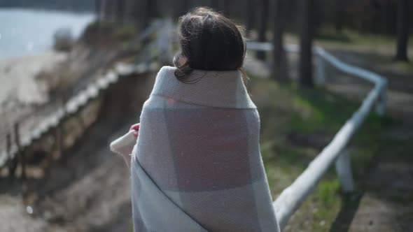 Happy Brunette Woman Wrapping in Blanket Turning Looking Away Smiling Standing on River Bank on