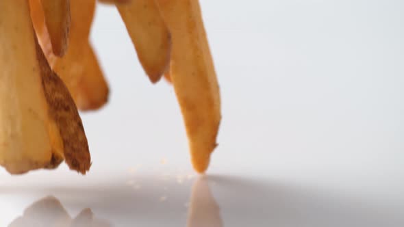 French fries falling on white surface. Slow Motion.