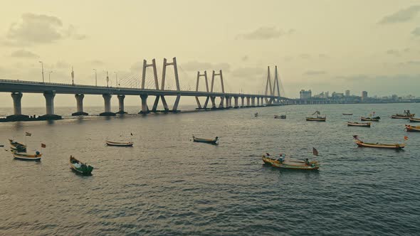 Aerial evening view of fishing boats sailing with Bandra Worli Sea Link in the background in Mumbai