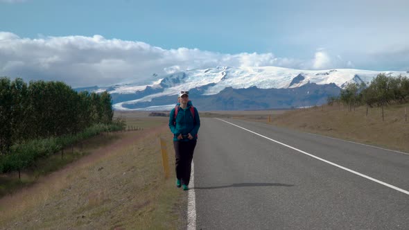 Woman Traveler with a Backpack Is on an Asphalt Road