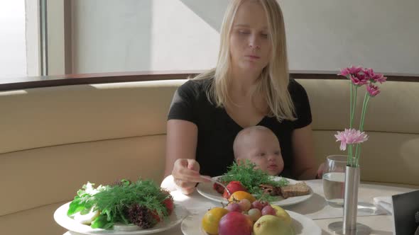 A Woman with a Baby on Her Lap Is Having a Meal