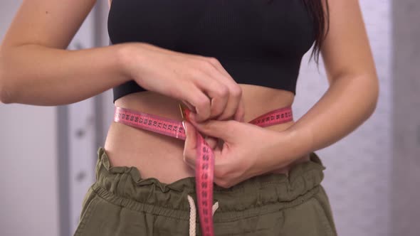 Woman Measuring Her Waist with a Meter Tape Loose Weight Dieting Concept