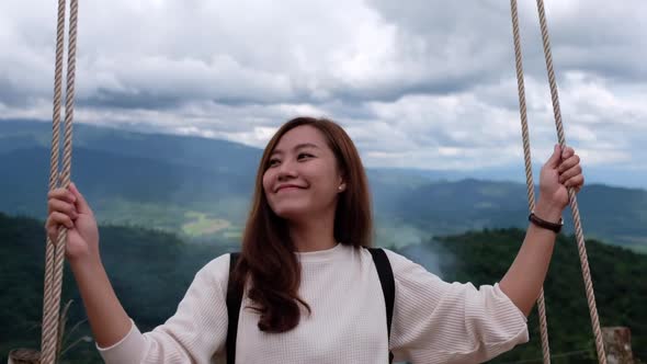 Slow motion of a woman sitting on a swing with a beautiful mountains view
