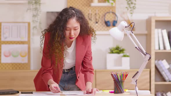 young entrepreneur working standing at desk at home office arranging papers, managing project tasks.