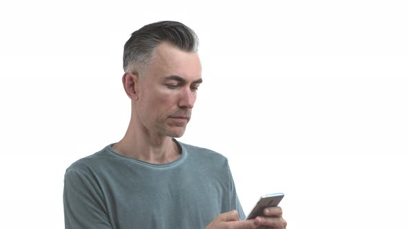 Handsome Slim Middleaged Man with Grey Hair and Bristle Shopping Online Holding Mobile Phone and