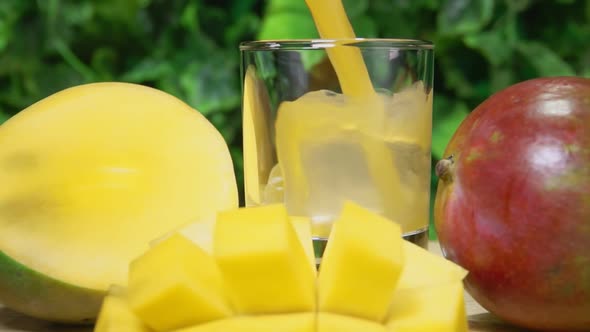 Mango Juice Is Poured Into the Glass Next To Large Ripe Mango Cut Into Slices