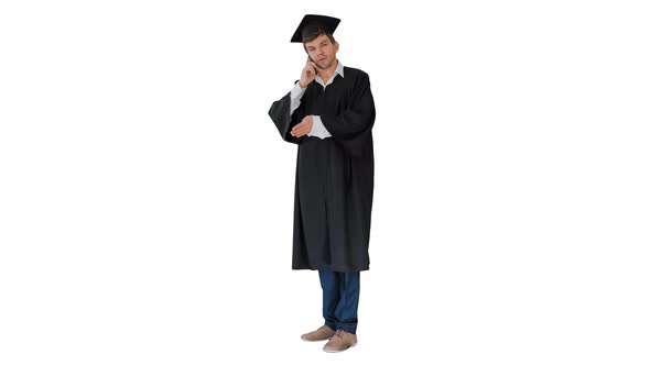 Male Graduate in Gown and Mortarboard Having Conversation on the Phone on White Background.