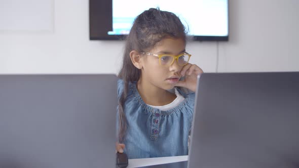 Focused Smart Schoolgirl in Glasses Using Laptop