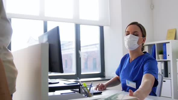 Female Doctor Offering Mask To Patient at Hospital