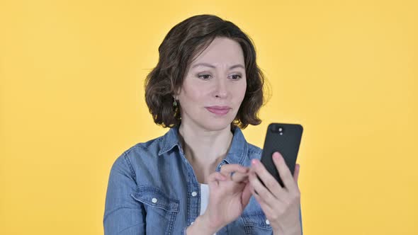 Old Woman Using Smartphone on Yellow Background 