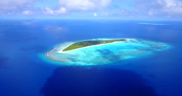 Daytime overhead tourism shot of a sandy white paradise beach and blue water background in hi res 4K