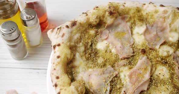 Pizza with Meat, Pesto, Cheese and Parmesan fresh out of the oven ready to eat.