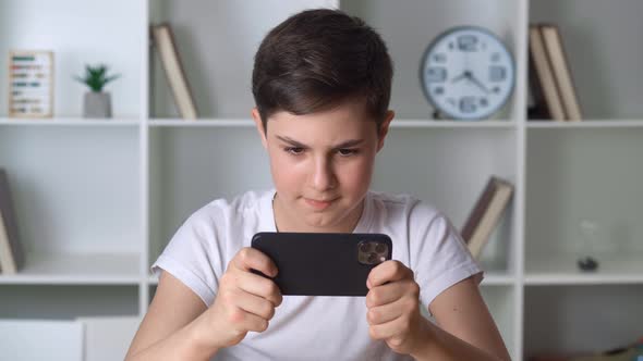 Beautiful Boy 13 Years Old Playing Mobile Game on Smartphone at Home