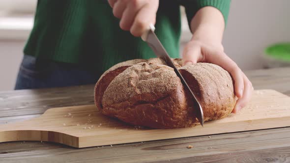 Hands of a Woman Cutting Bread Loaf on Wooden Cutting Board