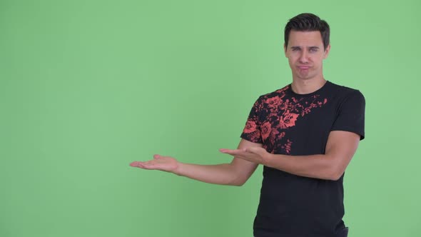 Stressed Young Man Showing Something and Giving Thumbs Down