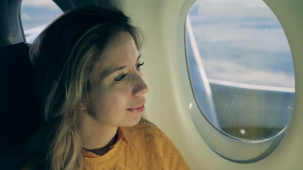 Close Up of Woman's Face While Looking Out of the Plane Window