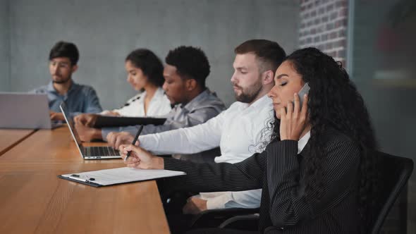 Focused Multiracial Employees Sitting in Conference Room Making Different Work Tasks Hispanic Woman