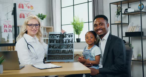 Man and His Cute Small Daughter which Posing on Camera Together with Female Doctor