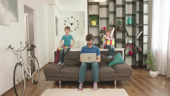 Young Father Looks After The Children At Home And Works At The Computer.