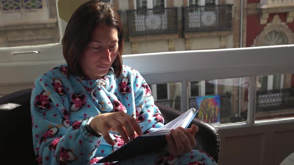 a Girl in Blue Pajamas Reading a Book in a Chair