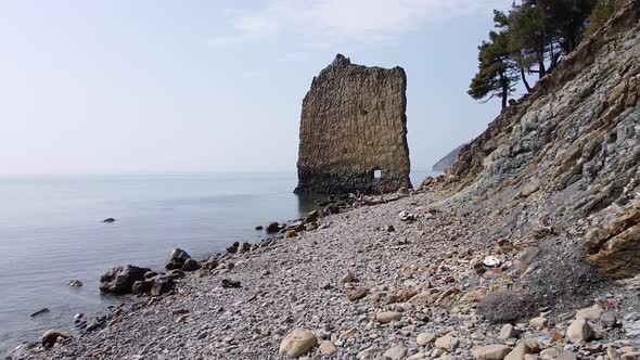 An unusual rock standing in the sea. Flat rock in the form of a sail with a hole in the middle