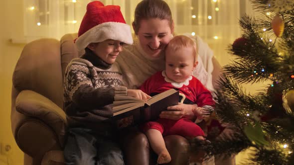 Baby Boy with Brother and Mother Reading Fairy Tale Book on Christmas Eve