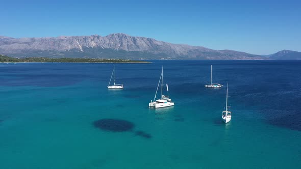 Sailboats, yachts and catamarans anchored on the shores with beach of the islands with vegetation in