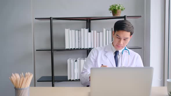 Young Asian doctor consult or online meeting via laptop in office and he look serious with work