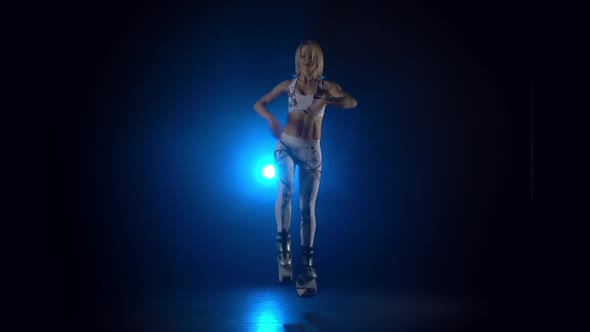 Woman Dancing in Kangoo Jumps Shoes Against Blue Spotlight. Slow Motion