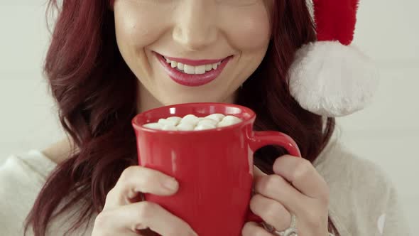 Attractive woman smiling holding a cup of cocoa with marshallows