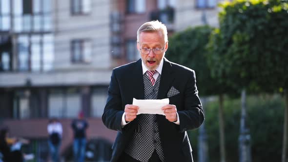 Portrait of a Senior Man Reading Paper Outdoors