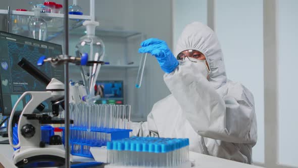 Lab Technician in Coverall Examining Samples of Liquid